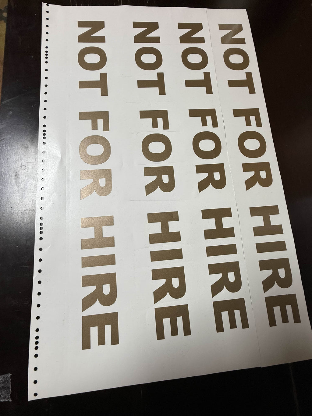 Column of four NOT FOR HIRE gold vinyl decals fresh off the cutter