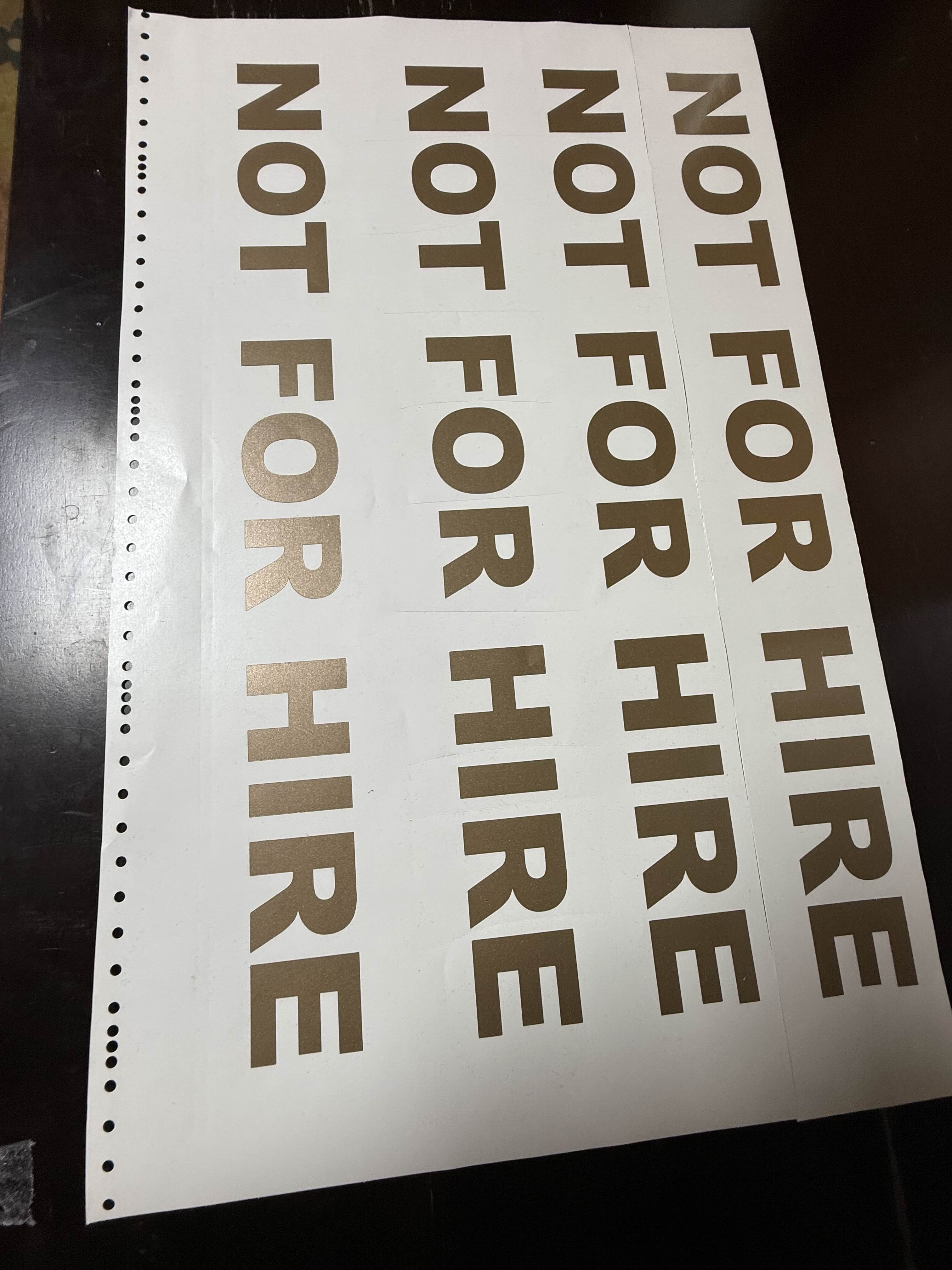 Column of four NOT FOR HIRE gold vinyl decals fresh off the cutter