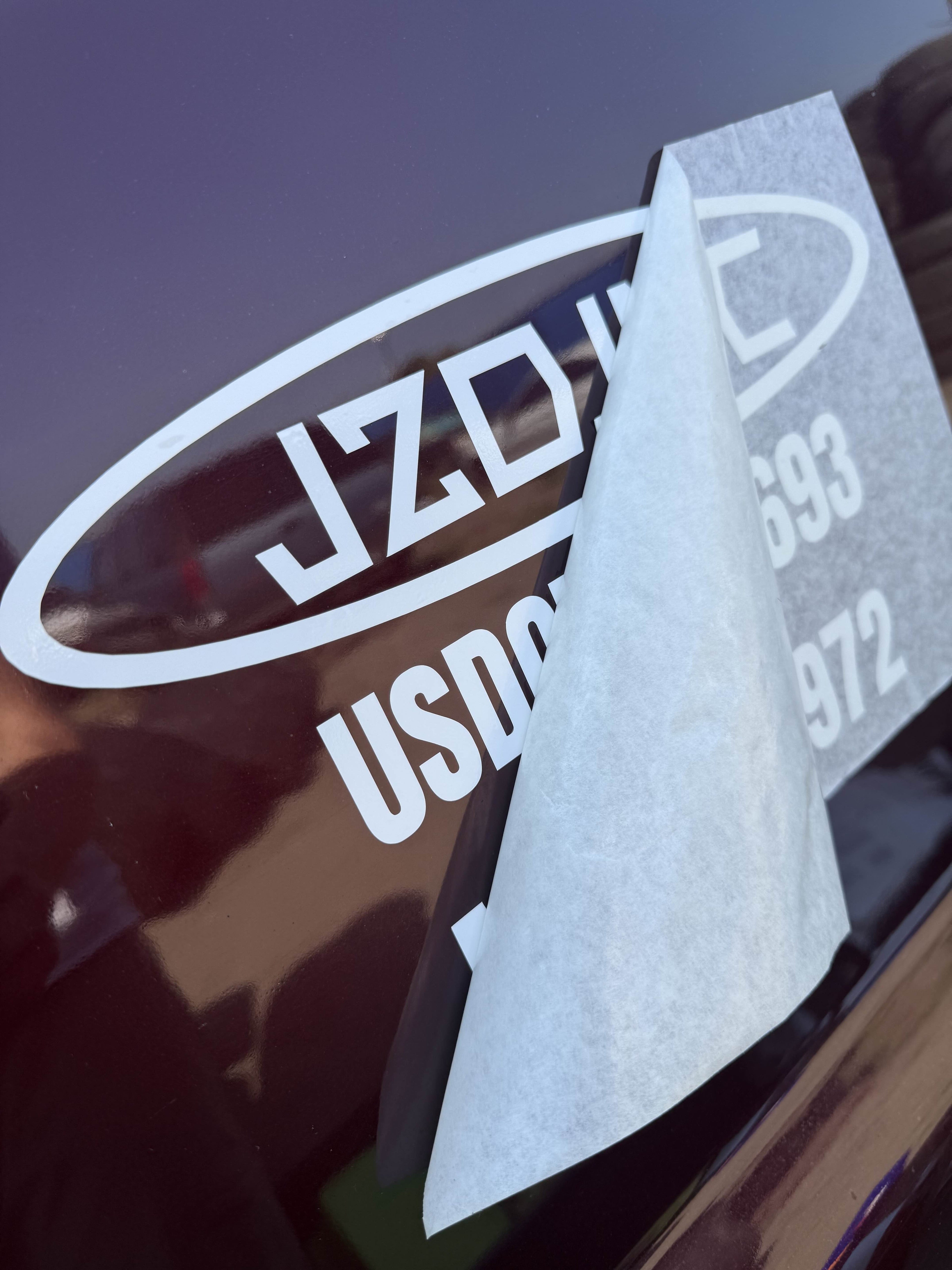 On-site vinyl installation - transfer tape being peeled back from freshly applied door lettering