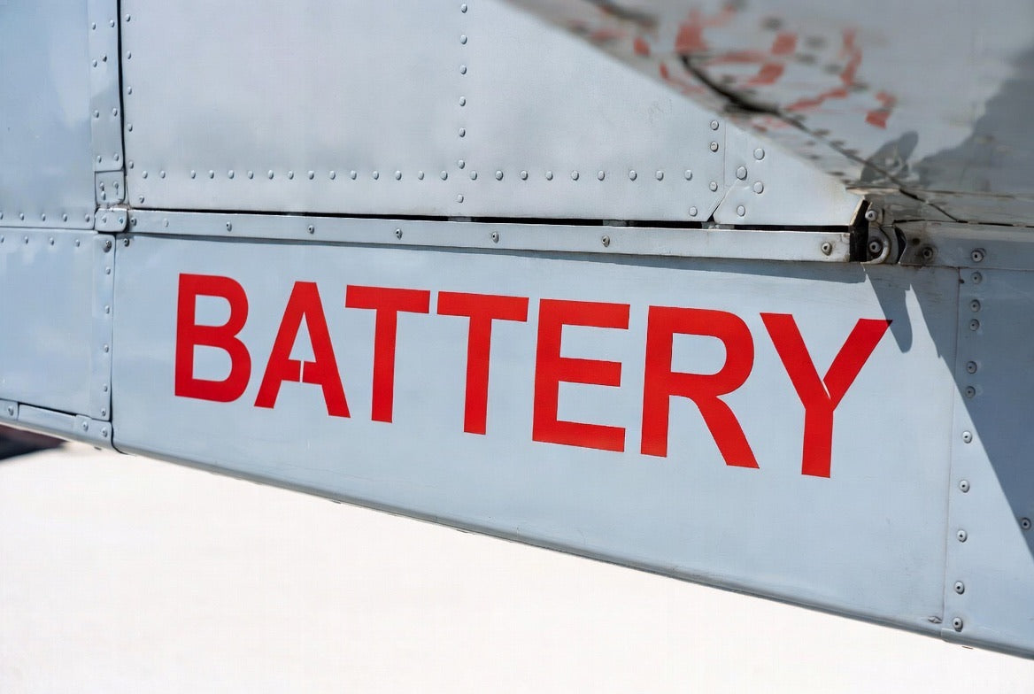 BATTERY placard applied to a grey aircraft access panel
