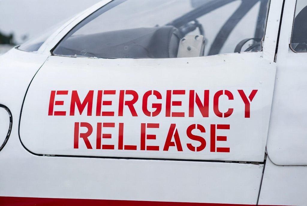 EMERGENCY RELEASE placard applied to a white aircraft cockpit door