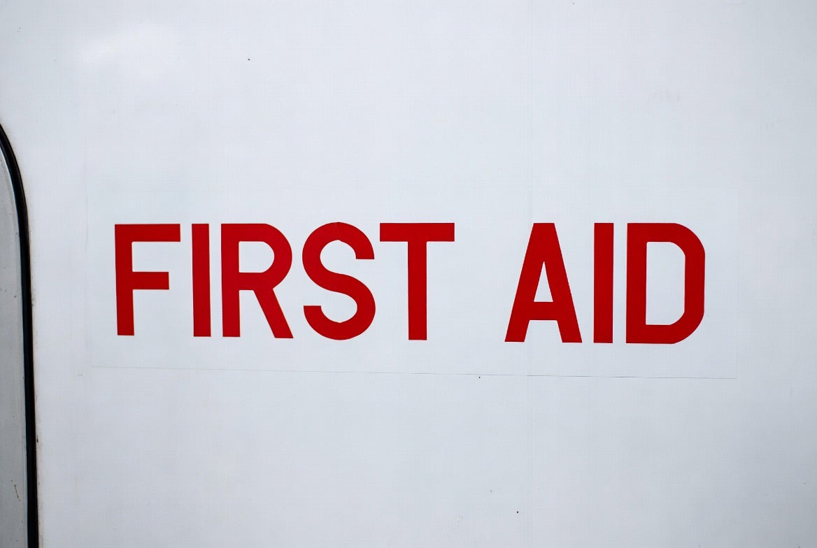 FIRST AID placard applied to a white aircraft cabin panel